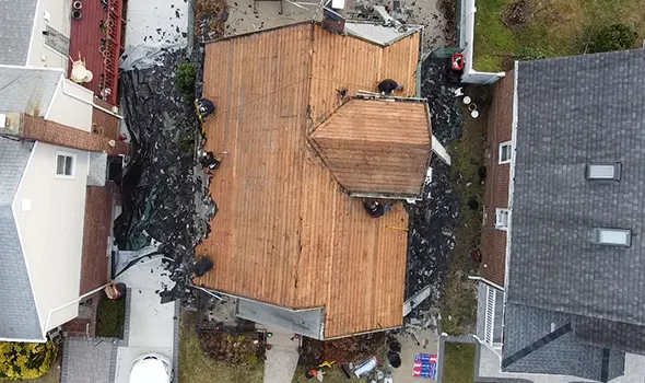 Aerial view of wooden roof decking partially covered during new roof installation on a residential building in Manhattan, NY.
