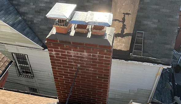 Close-up of brick chimney with fresh mortar repair work on a residential roof in The Bronx, NY.